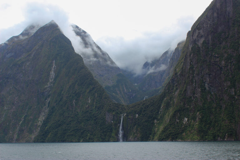 Monumental mountains over the dark waves of Milford Sound.