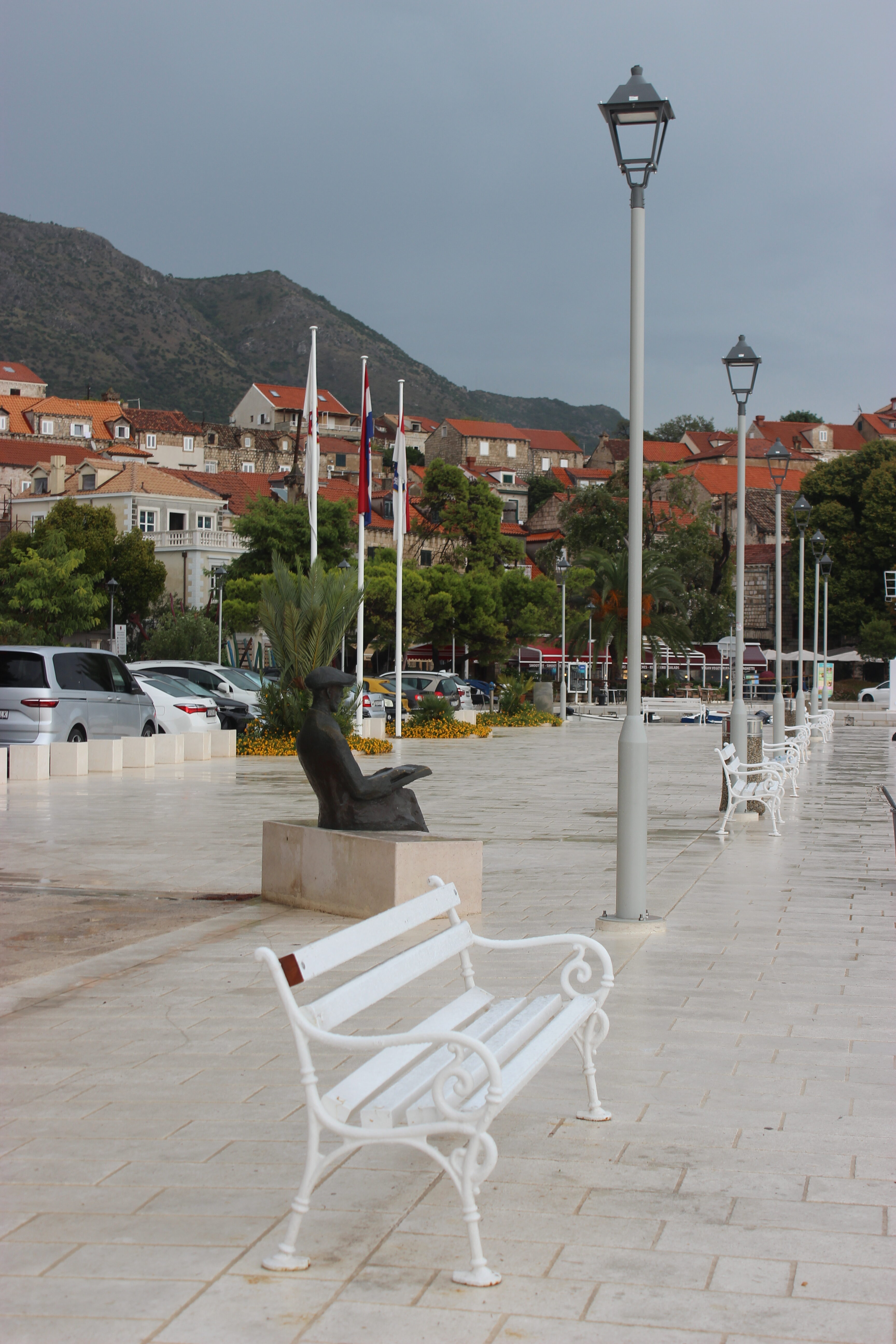 A rainy sidewalk and bench in Cavtat, Croatia.