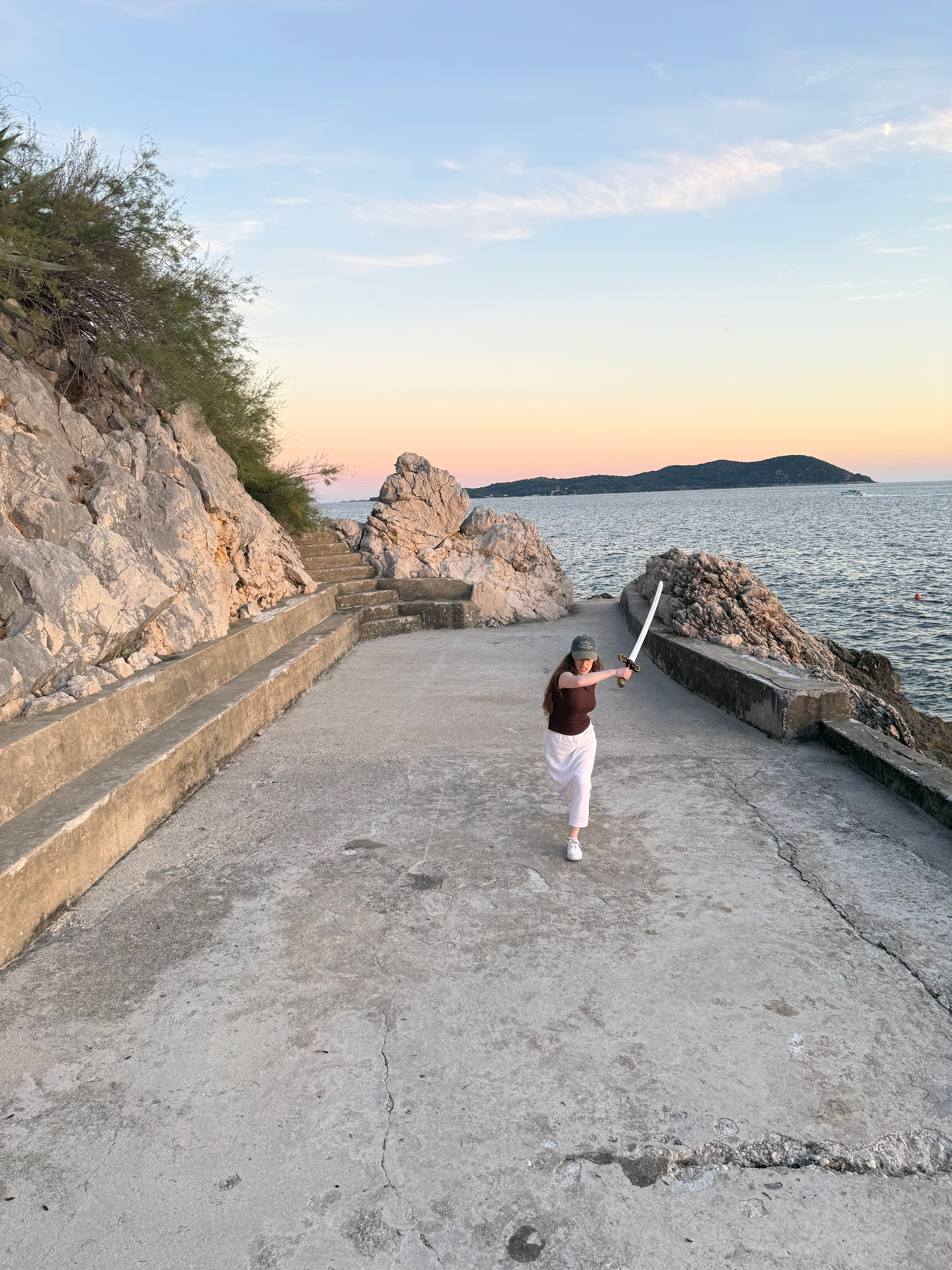 Bella pretending to sword fight on the stone platform in Trsteno.