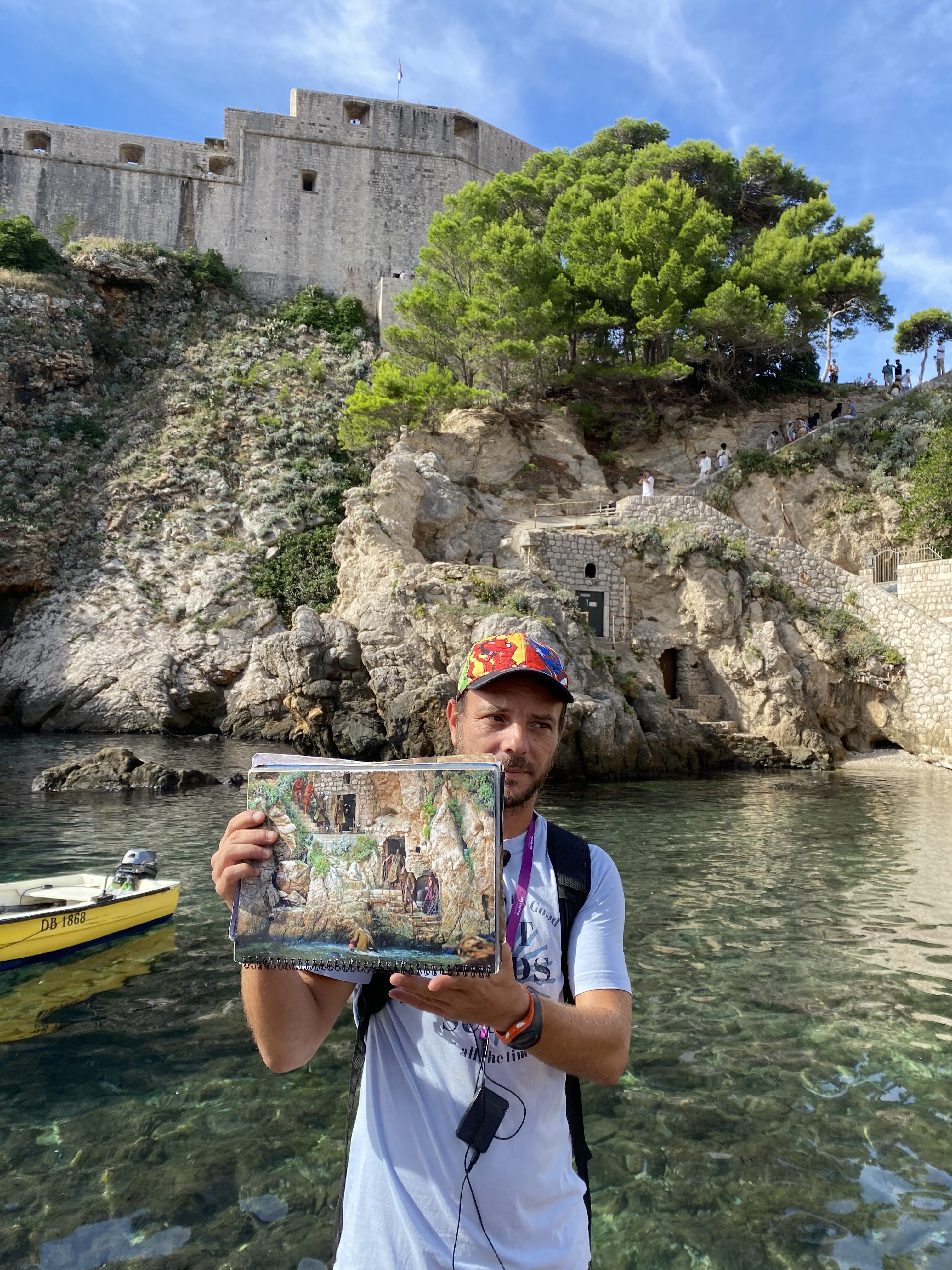 A tour guide in Dubrovnik holding a picture of a Game of Thrones scene in front of the filming location, Fort Lovrijenac in Dubrovnik.