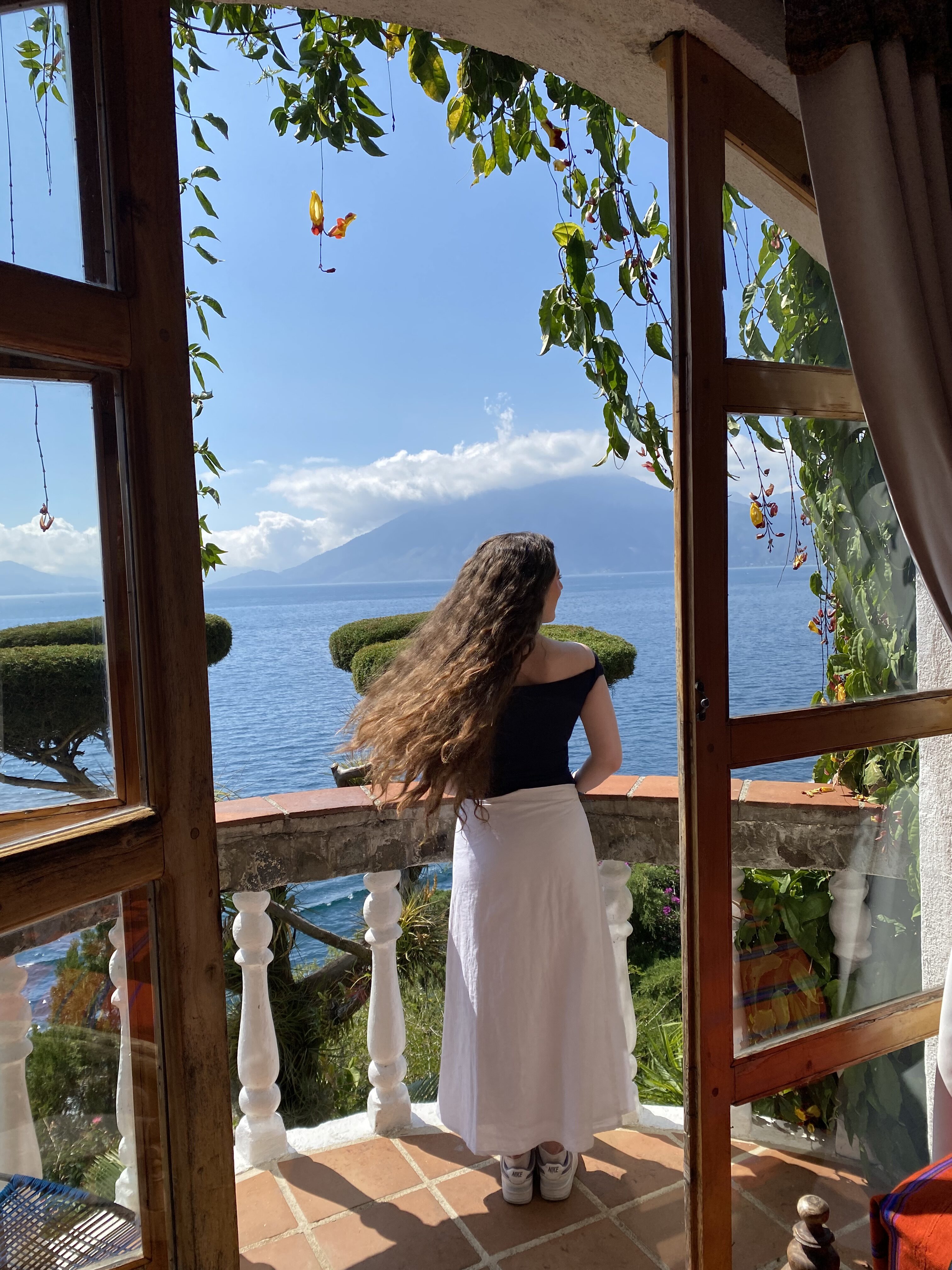 Woman with brunette hair gazing out from a balcony suite at La Casa del Mundo.