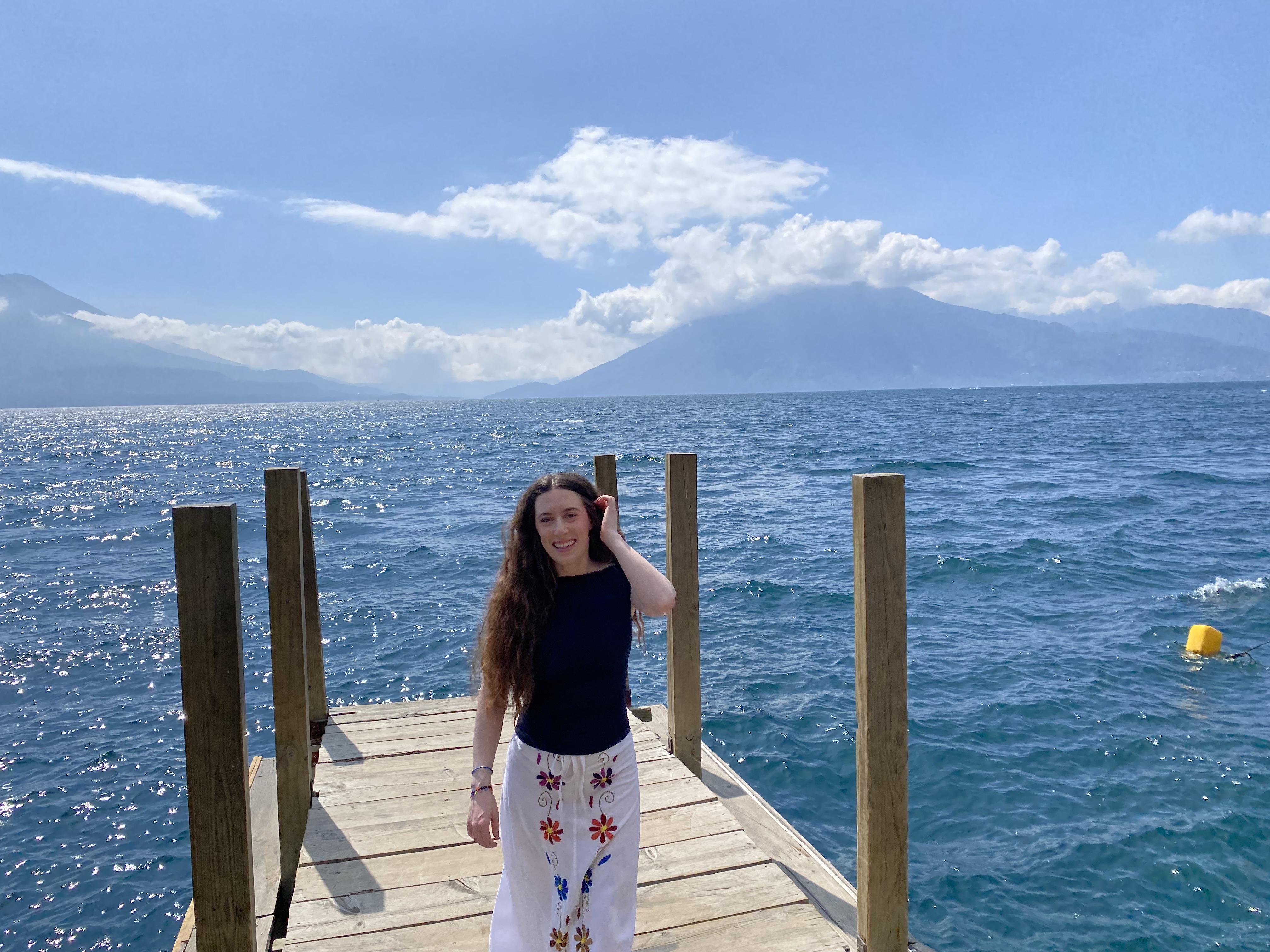 Bella posing on a dock at Lake Atitlán with Atitlán and San Pedro Volcanoes in the background.
