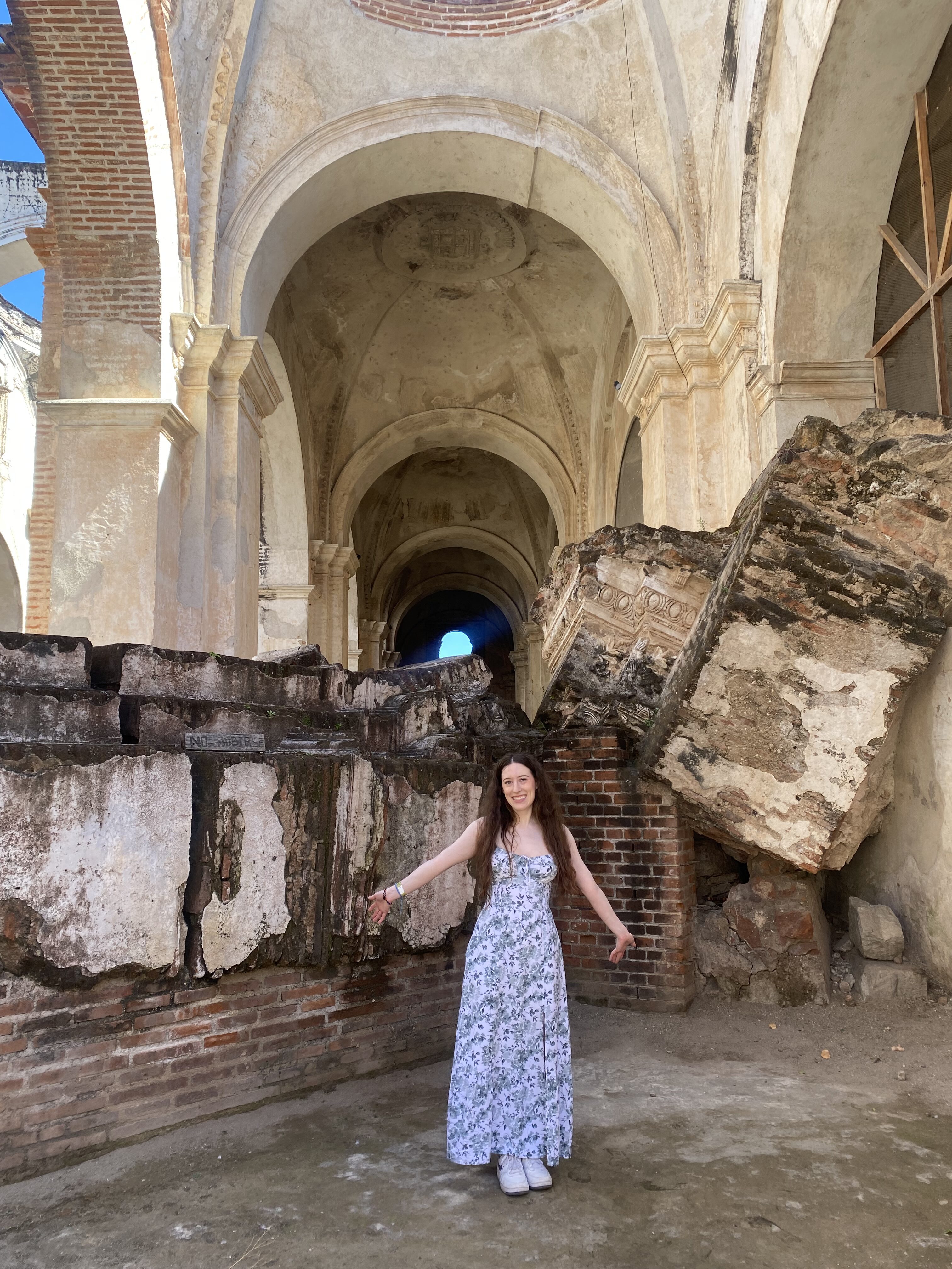 Bella, posing in a white and green sundress in front of the ruins of Catedral de San José.
