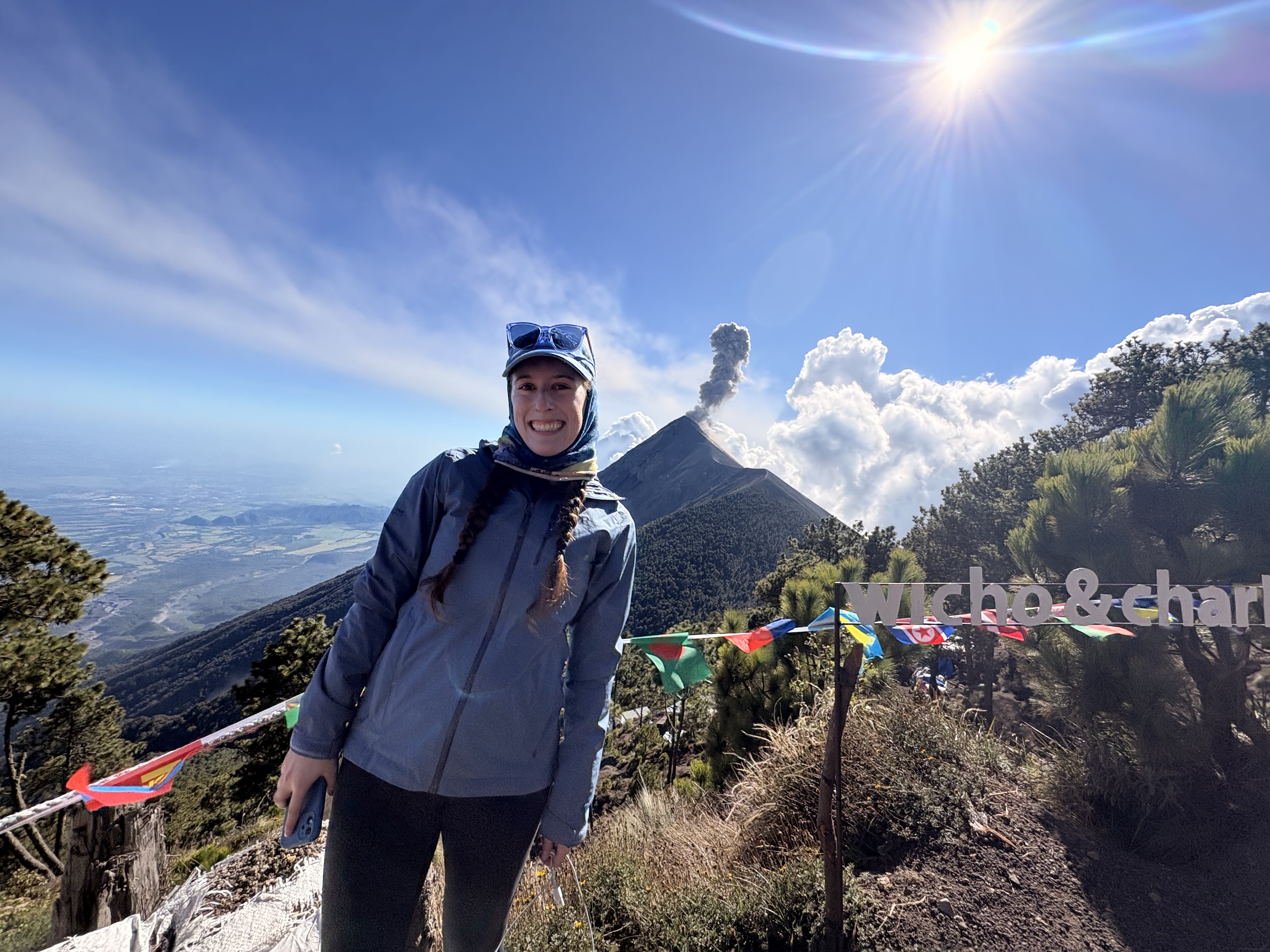 Bella smiling in front of the smoking Fuego Volcano at Wicho and Charlie's Acatenango Base Camp.