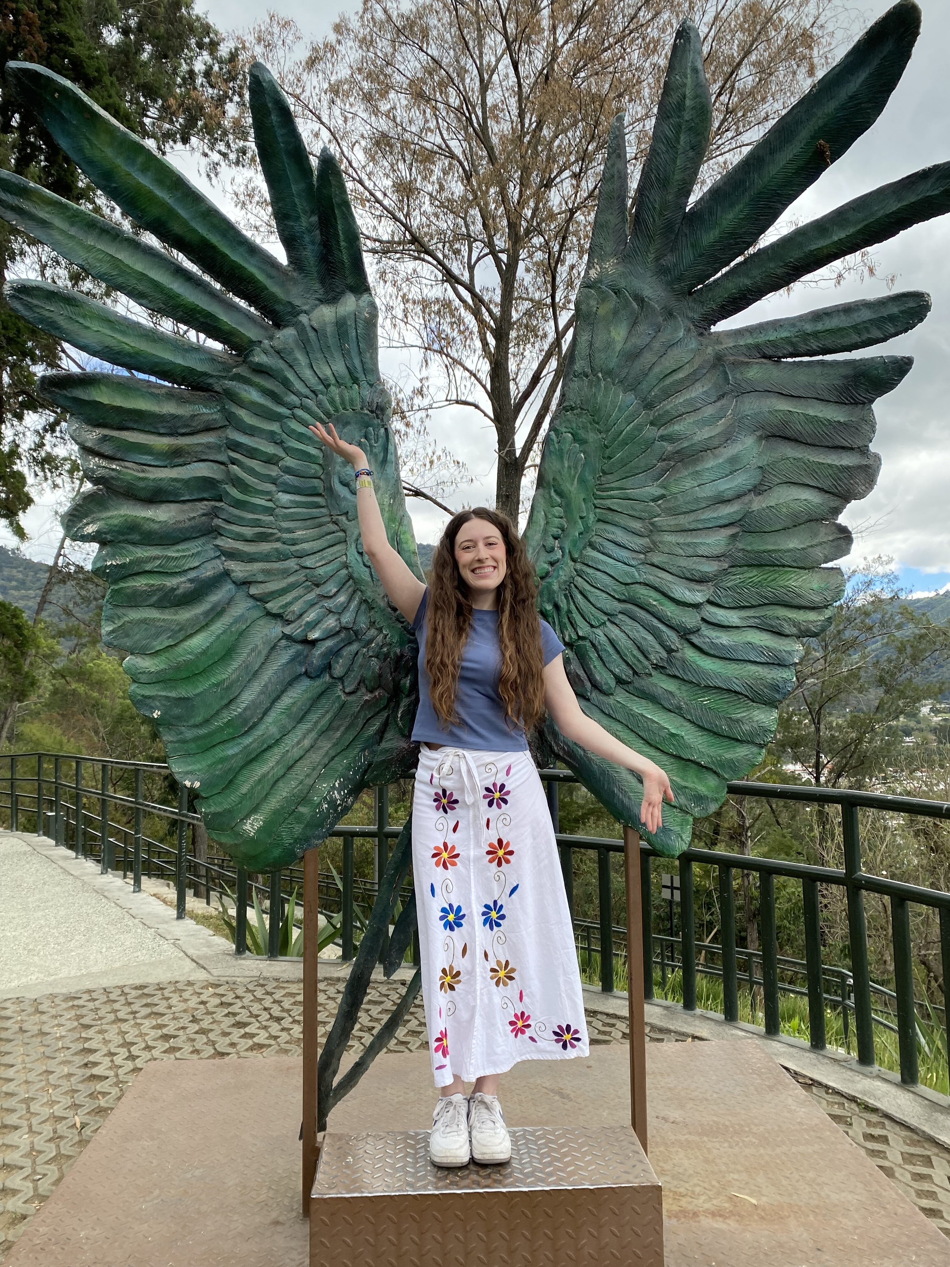 Bella posing in front of large green wings at Cerro de la Cruz, Antigua (Guatemala).