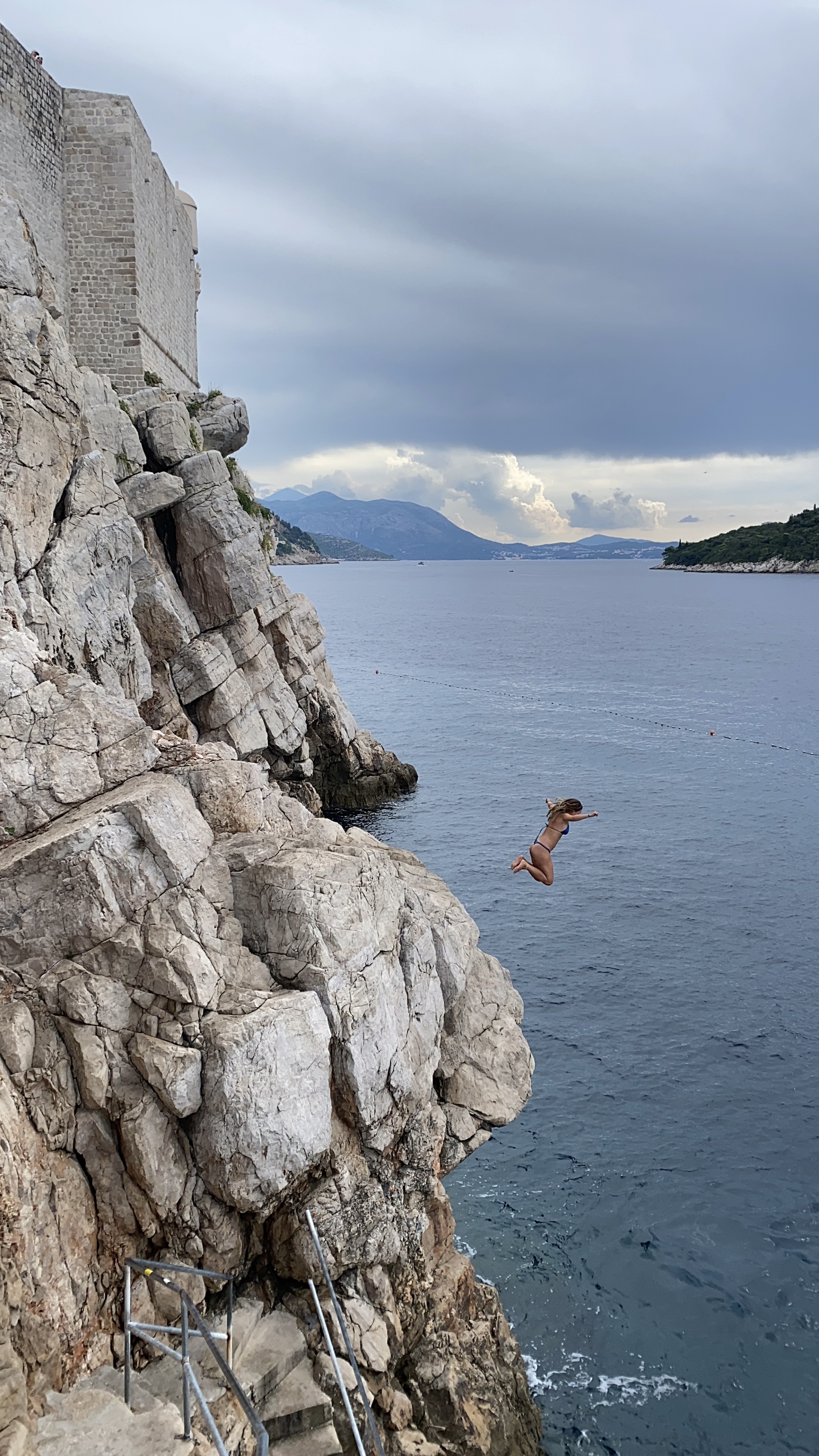 Young woman cliff jumping in Dubrovnik.