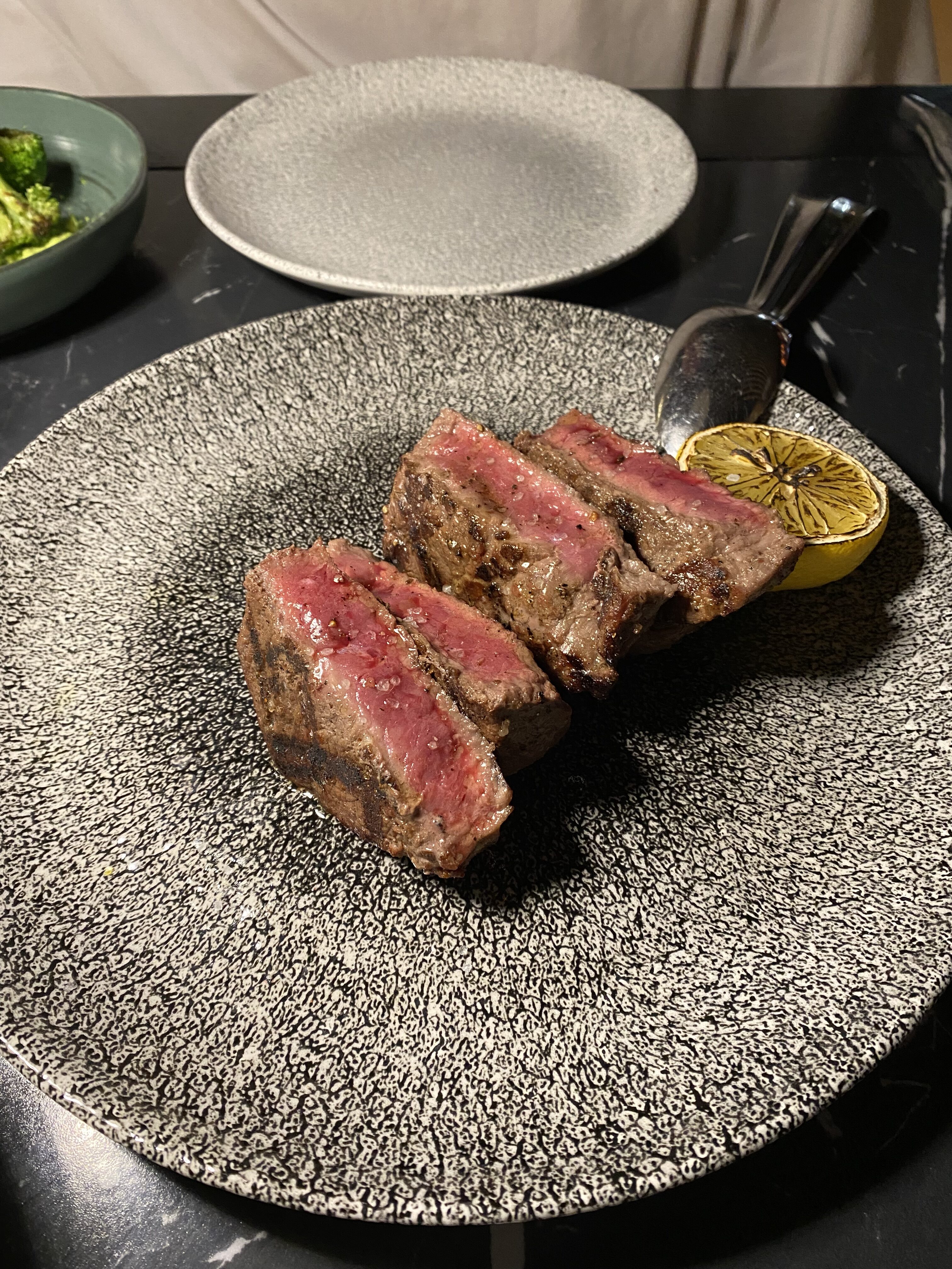 A speckled plate with thin cuts of medium rare steak with a charred lemon from EZZA Dubrovnik.