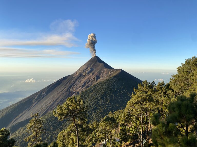 The ashy Fuego volcano in Guatemala with a plume of smoke erupting from the top.