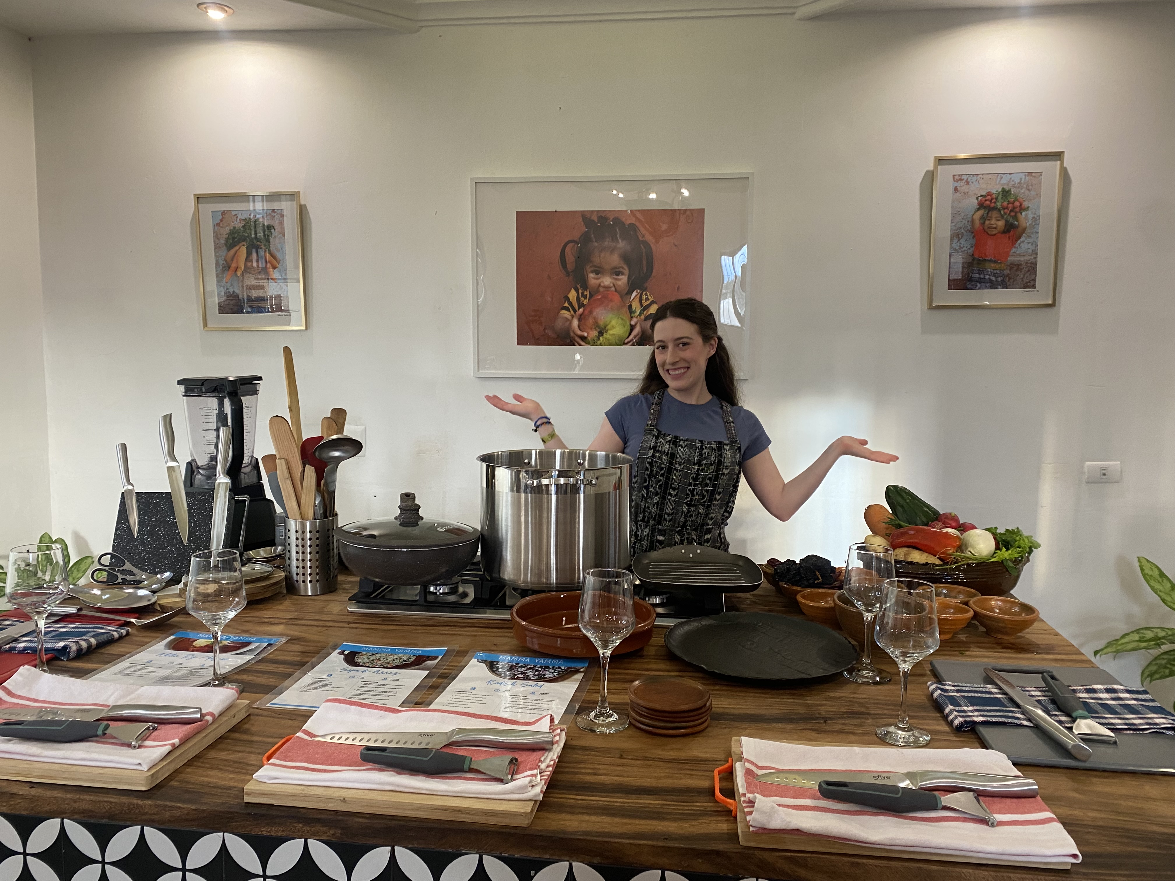 A young woman posing with her arms out in front of a cooking station at a Guatemala cooking class.