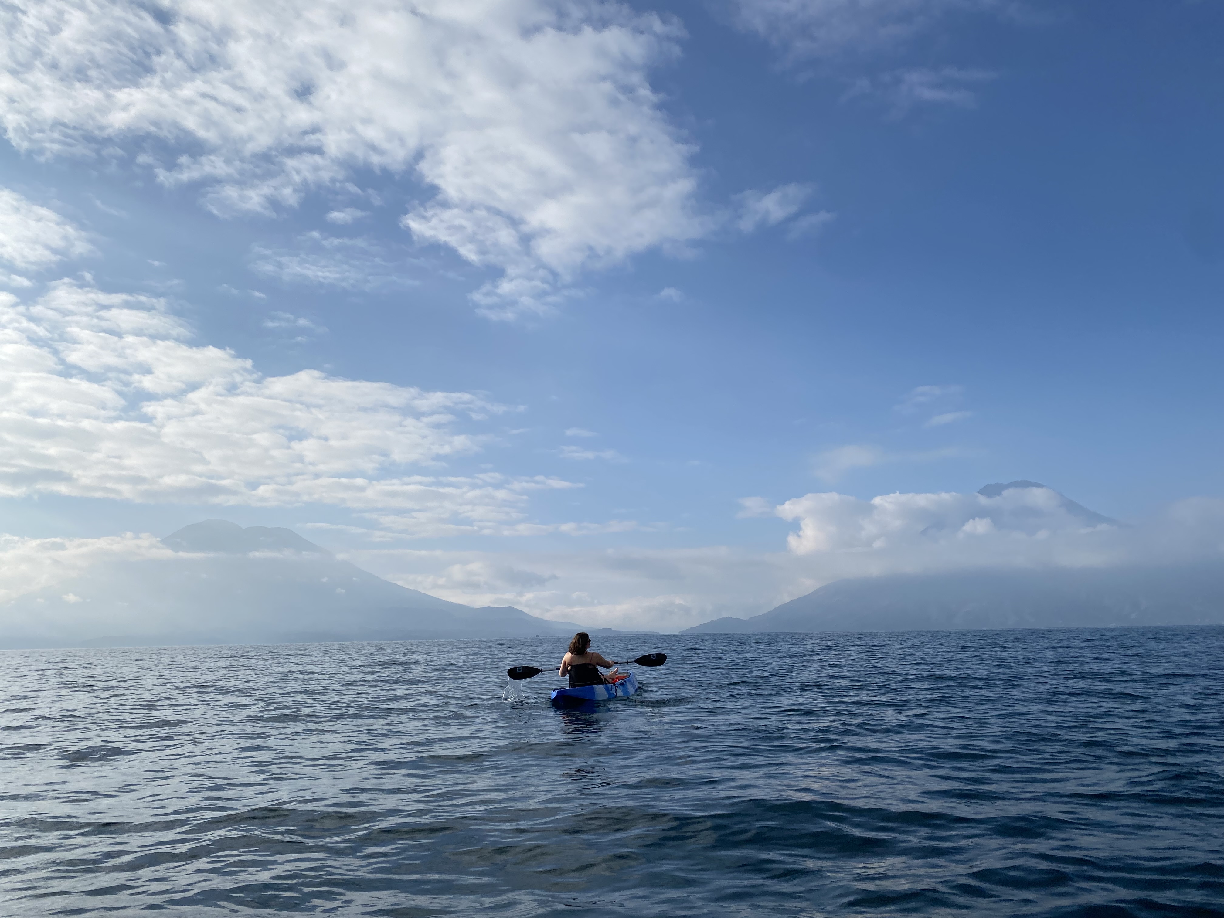 A kayaker on Lake Atitlán framed by two monumental volcanoes in the background.