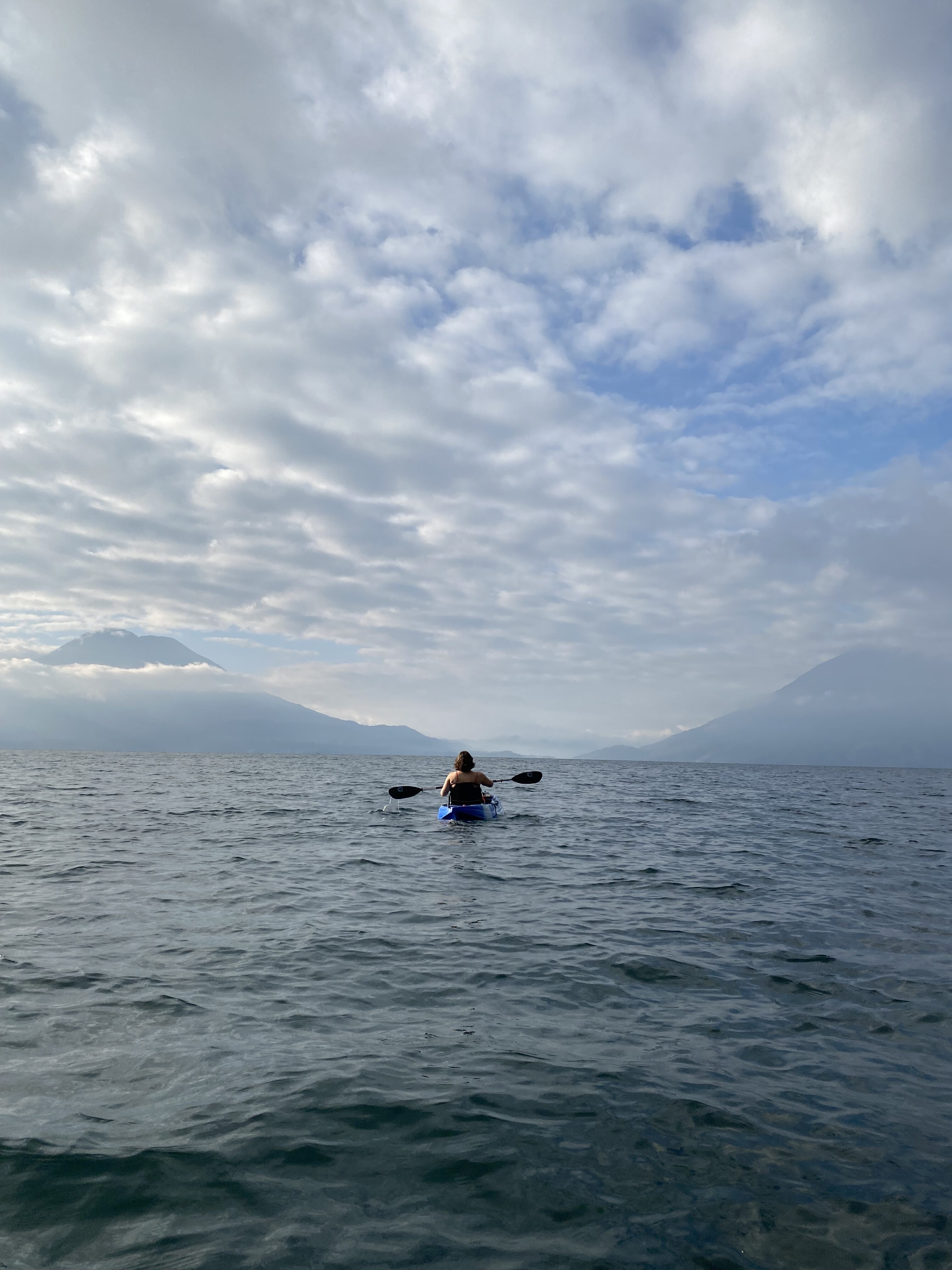 A kayaker on Lake Atitlán with two large volcanoes in the background (Atitlán and San Pedro Volcanoes).