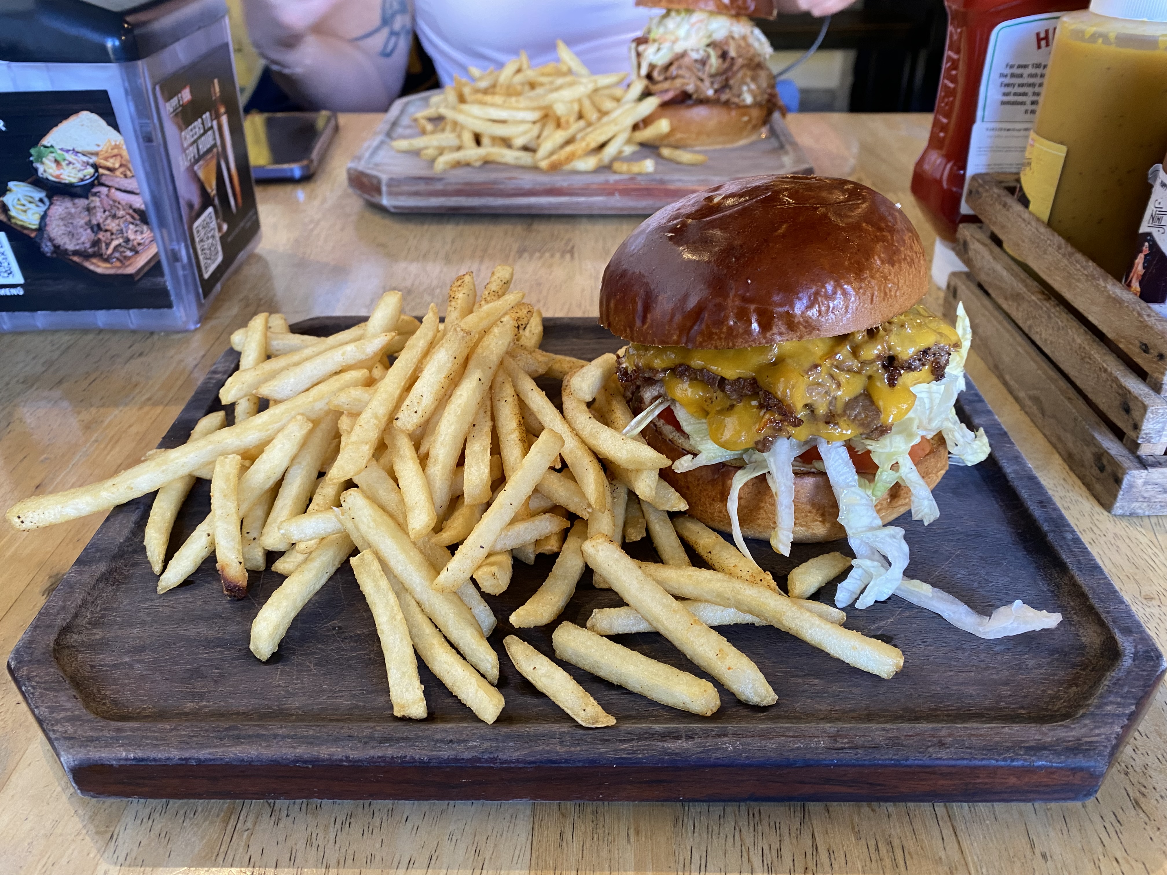 A wooden board with thin french fries and a greasy American burger from Pappy's BBQ in Antigua.