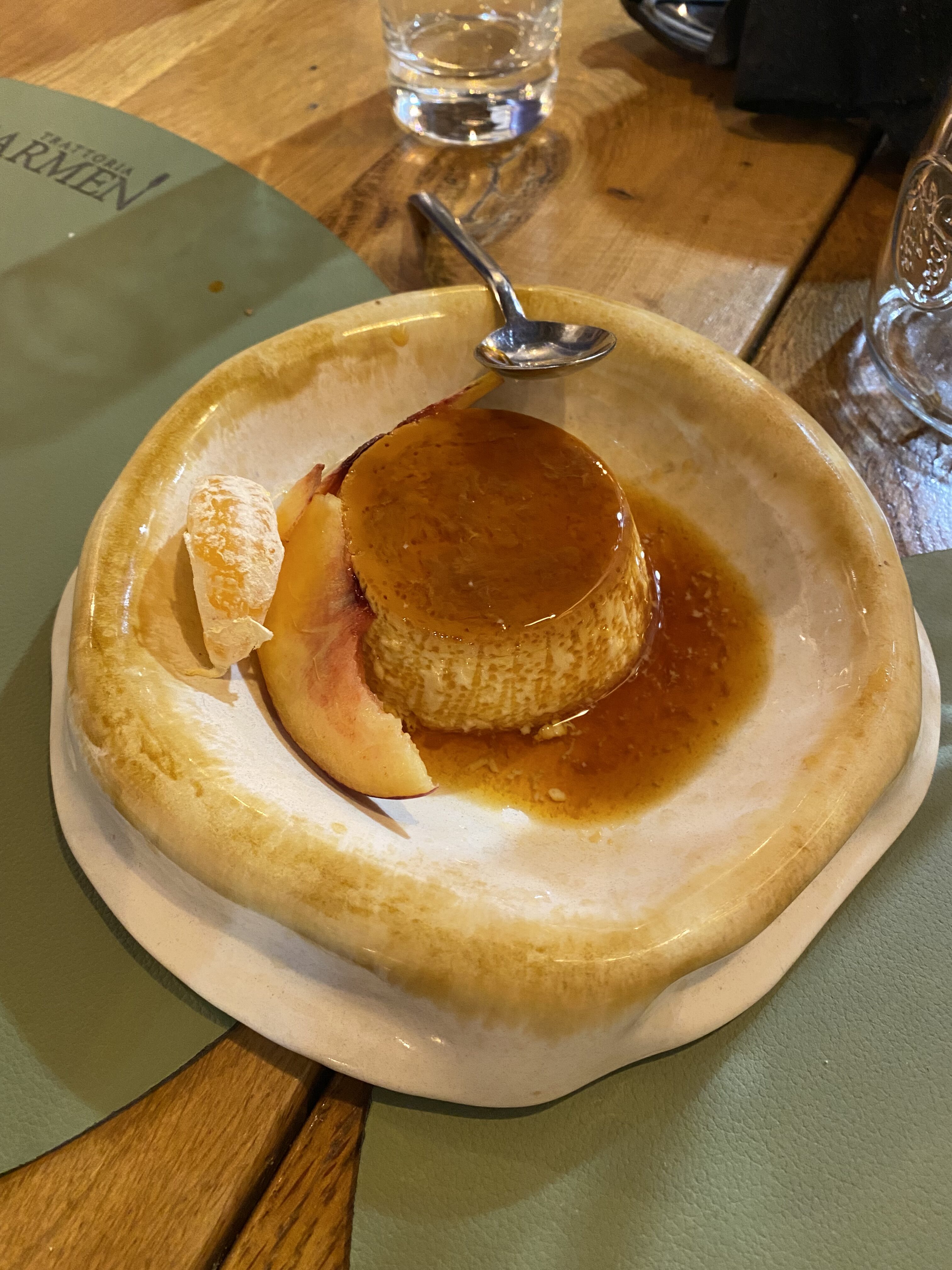A beautifully plated Croatian dessert, Rožata, with slices of fruit and a caramel sauce.