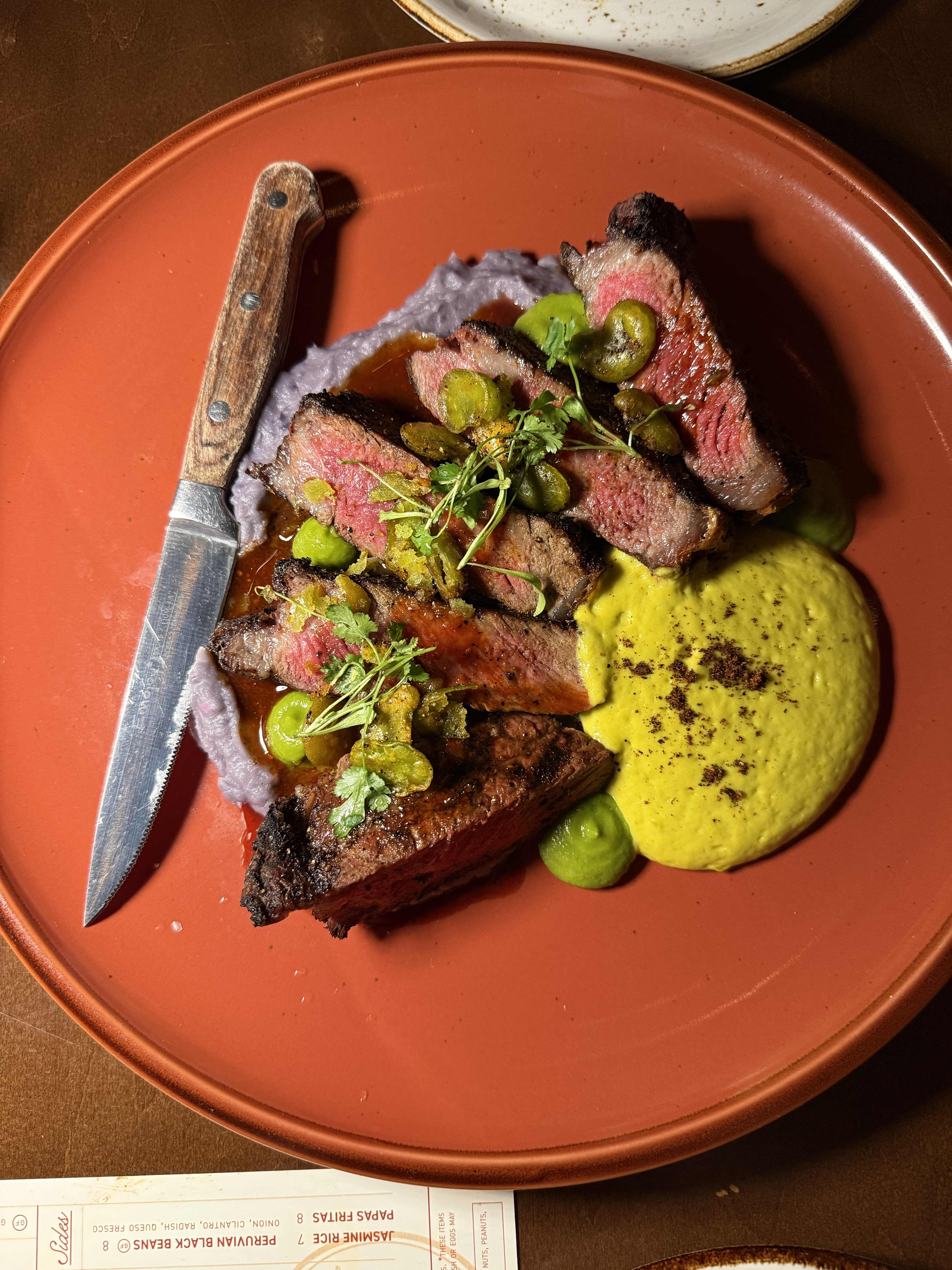 Bésame steak with a green sauce and purple mashed potatoes.