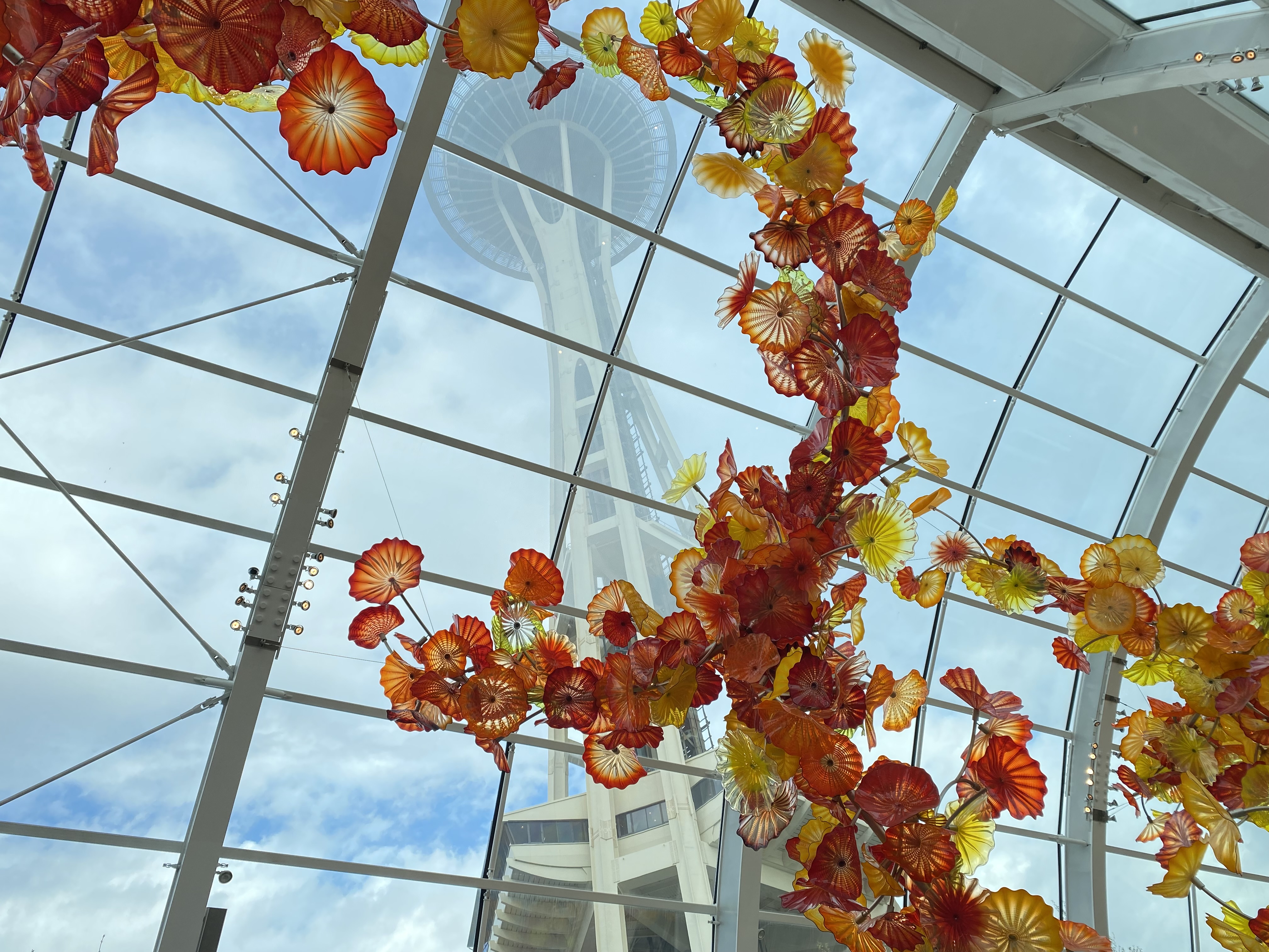 Decorate orange glass at the Chihuly Glass Museum framing the Space Needle through the window.