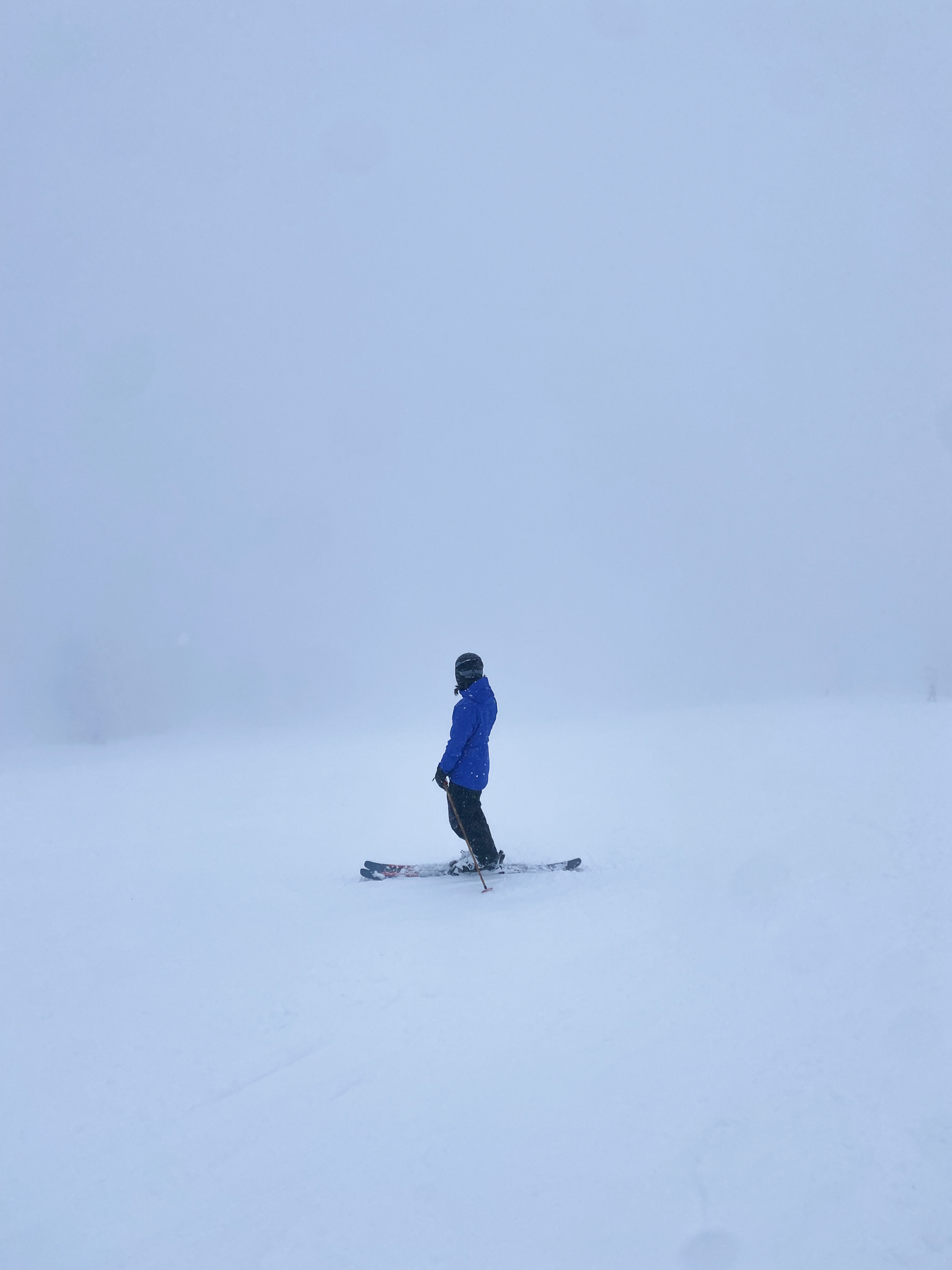 Skier with a blue coat looking out into a white landscape at Steamboat Springs Ski Resort.