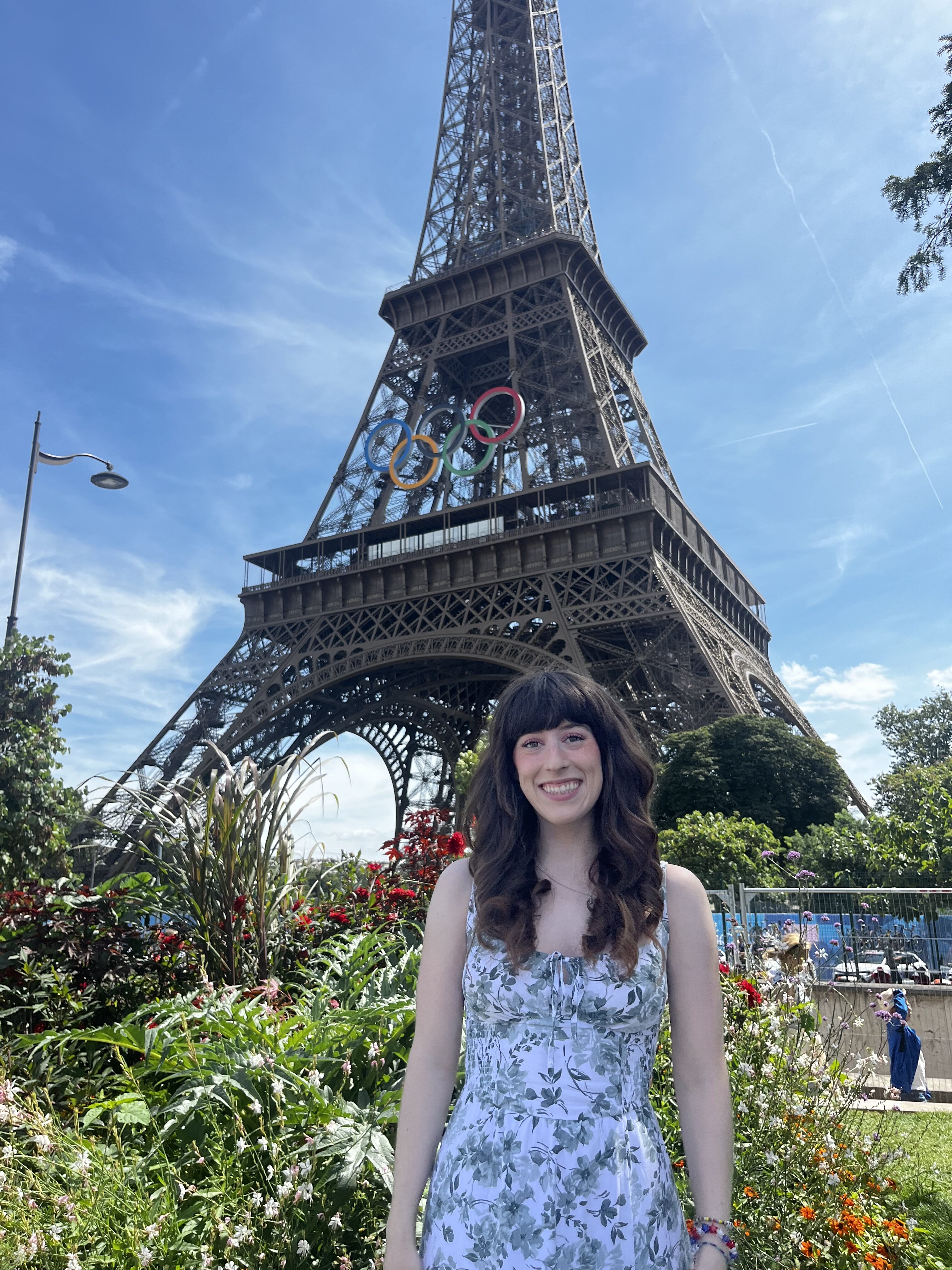 Bella smiling in front of the Eiffel Tower with the Olympic Rings