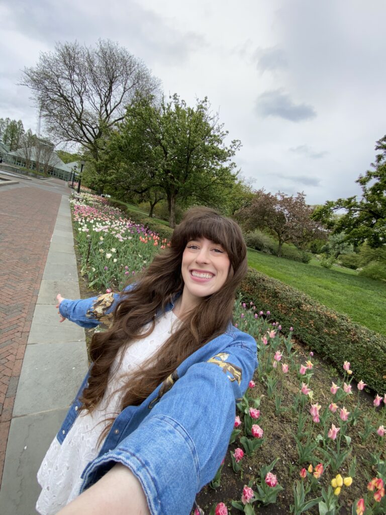 Bella smiling in front of the blooming tulips at the Brooklyn Botanic Gardens.