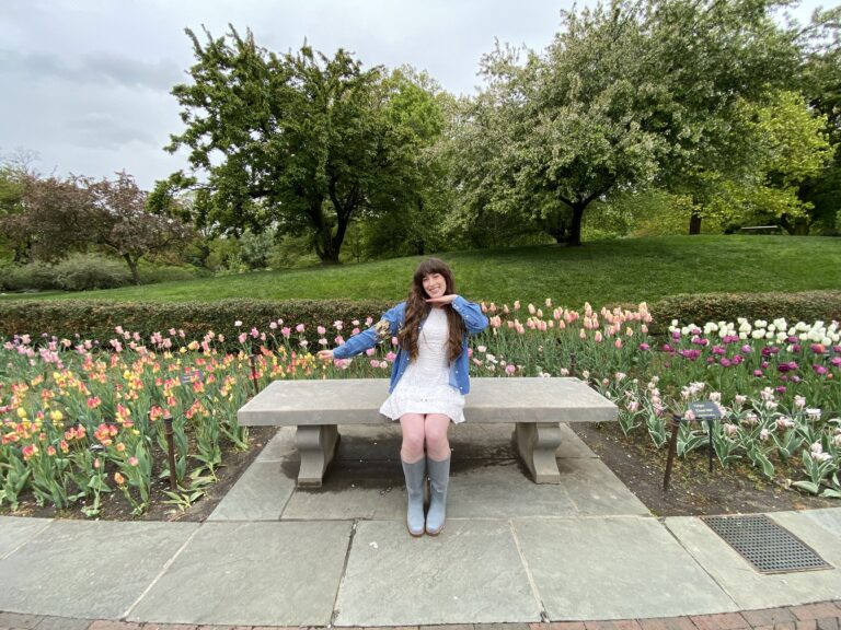 Bella posing on a bench in front of a variety of colorful tulips at the Brooklyn Botanic Garden.