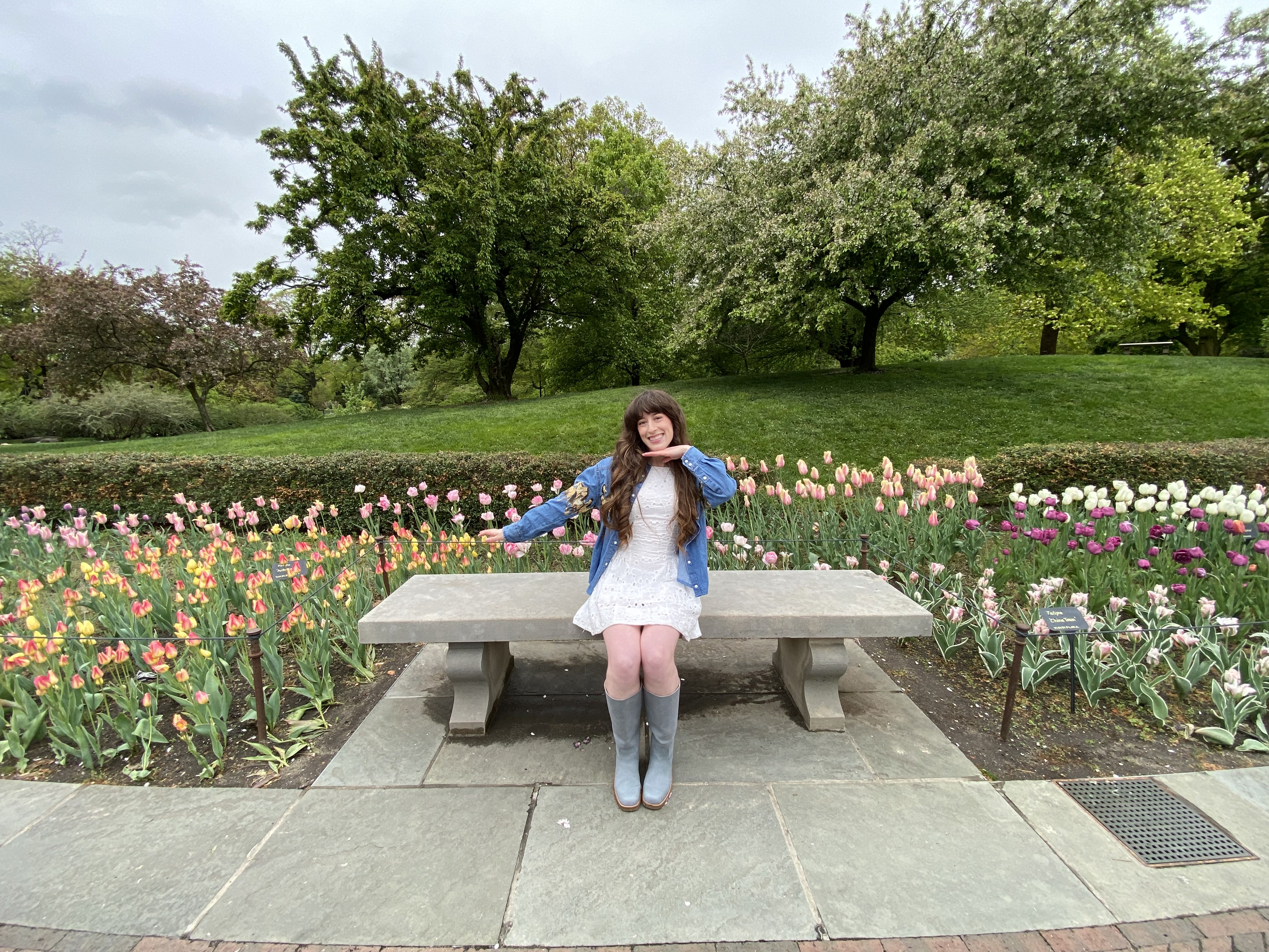 Bella posing on a bench in front of a variety of colorful tulips at the Brooklyn Botanic Garden.