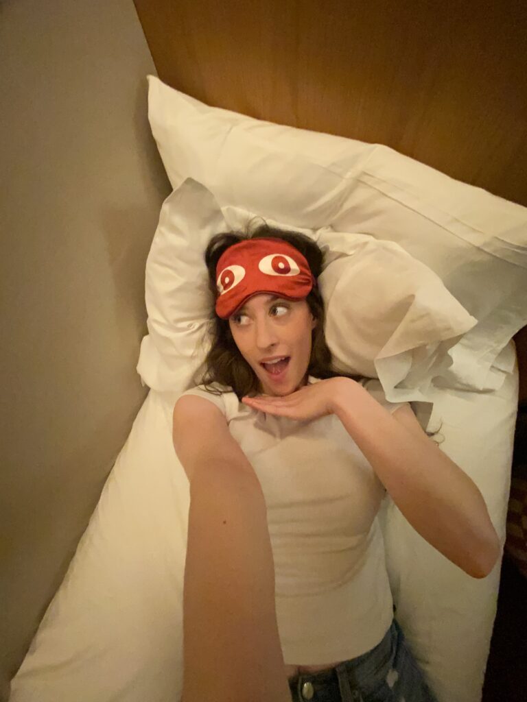 Bella posing with a pink eye mask in the capsule bed at Now Now hotel.