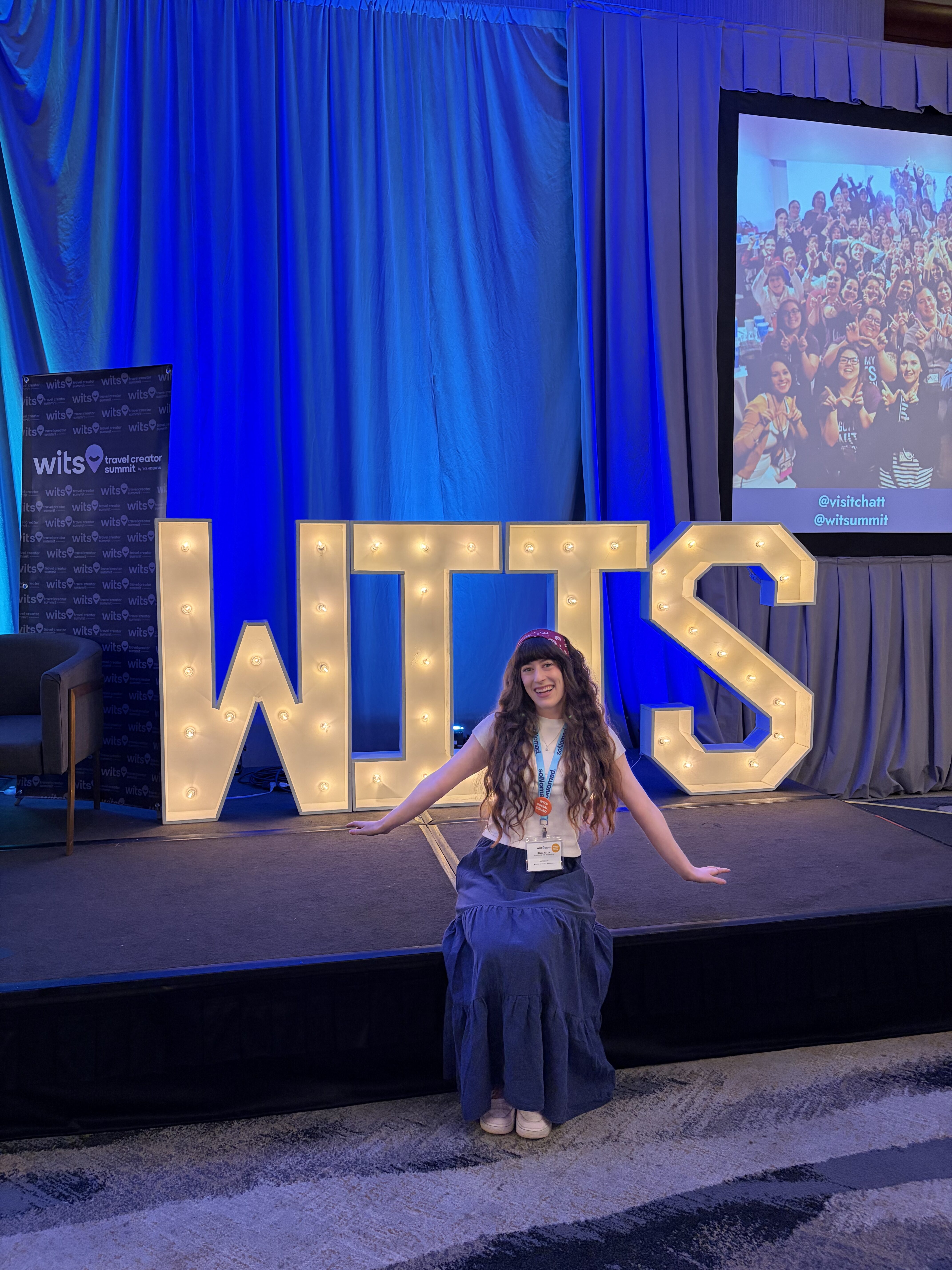Bella posing with an illuminated sign that says WITS. 