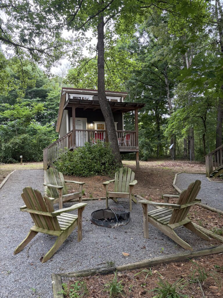 Wooden bungalow with wooden lawn chairs in front of the woods, Adventures Unlimited.