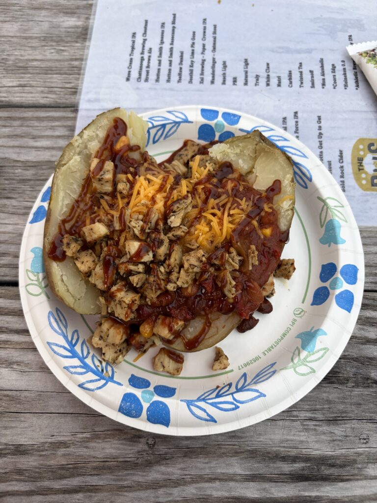 Baked potato with chili and chicken on a paper plate at Adventures Unlimited.