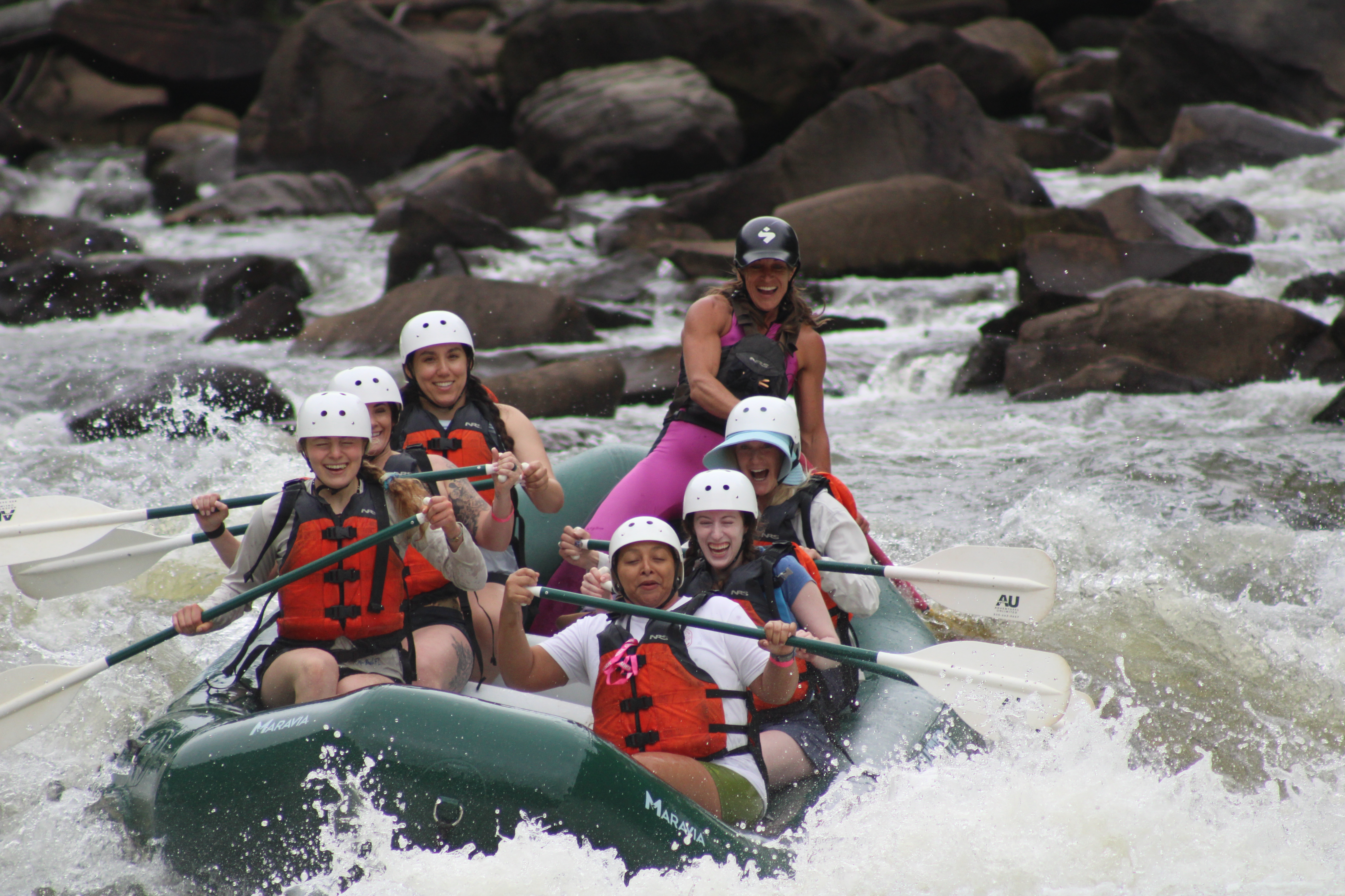 A group of rafters guided down the Ocoee River, smiling on a green raft.