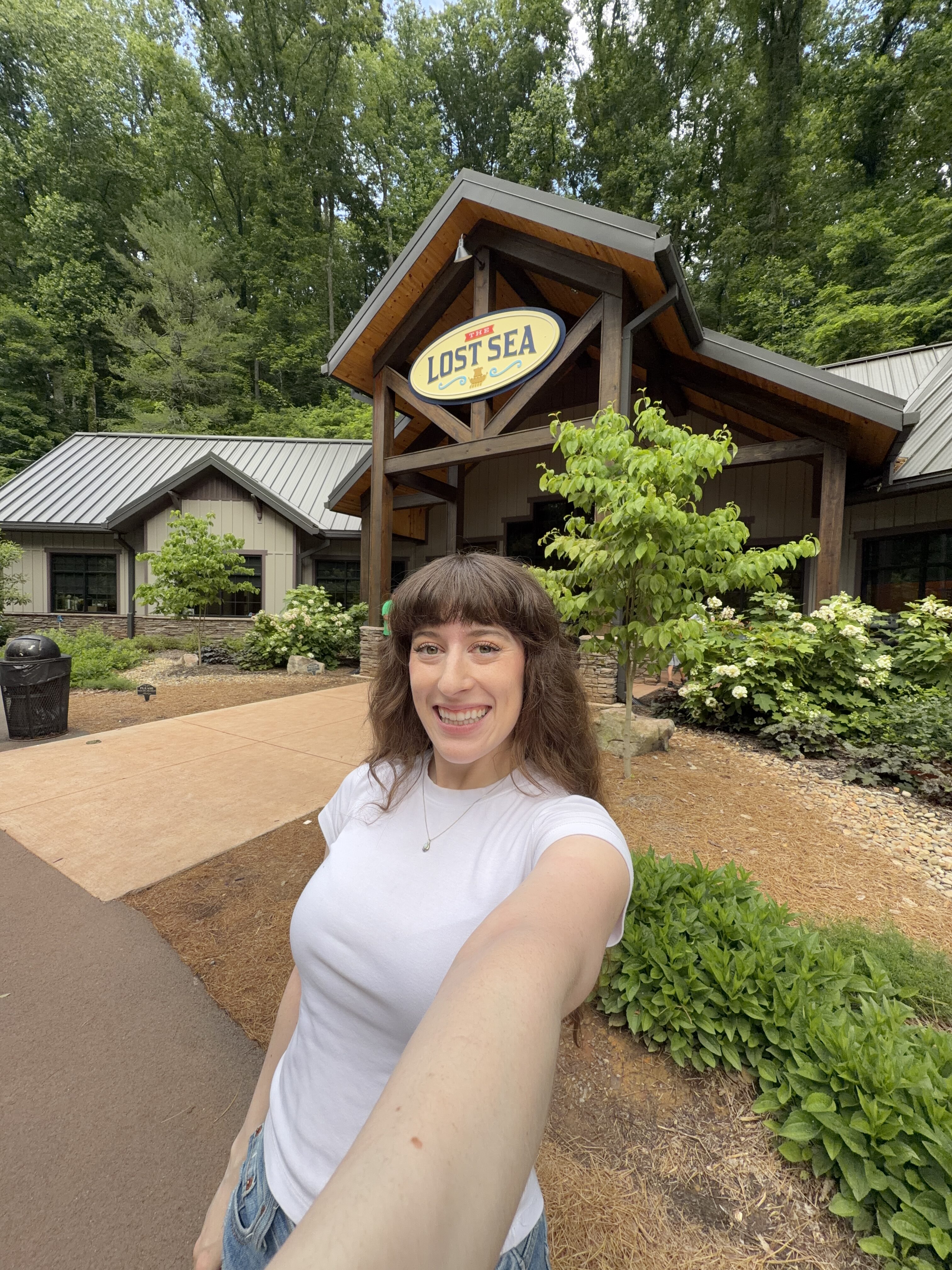 Bella, smiling for a selfie in front of the Lost Sea Adventure entrance in Sweetwater, Tennessee.