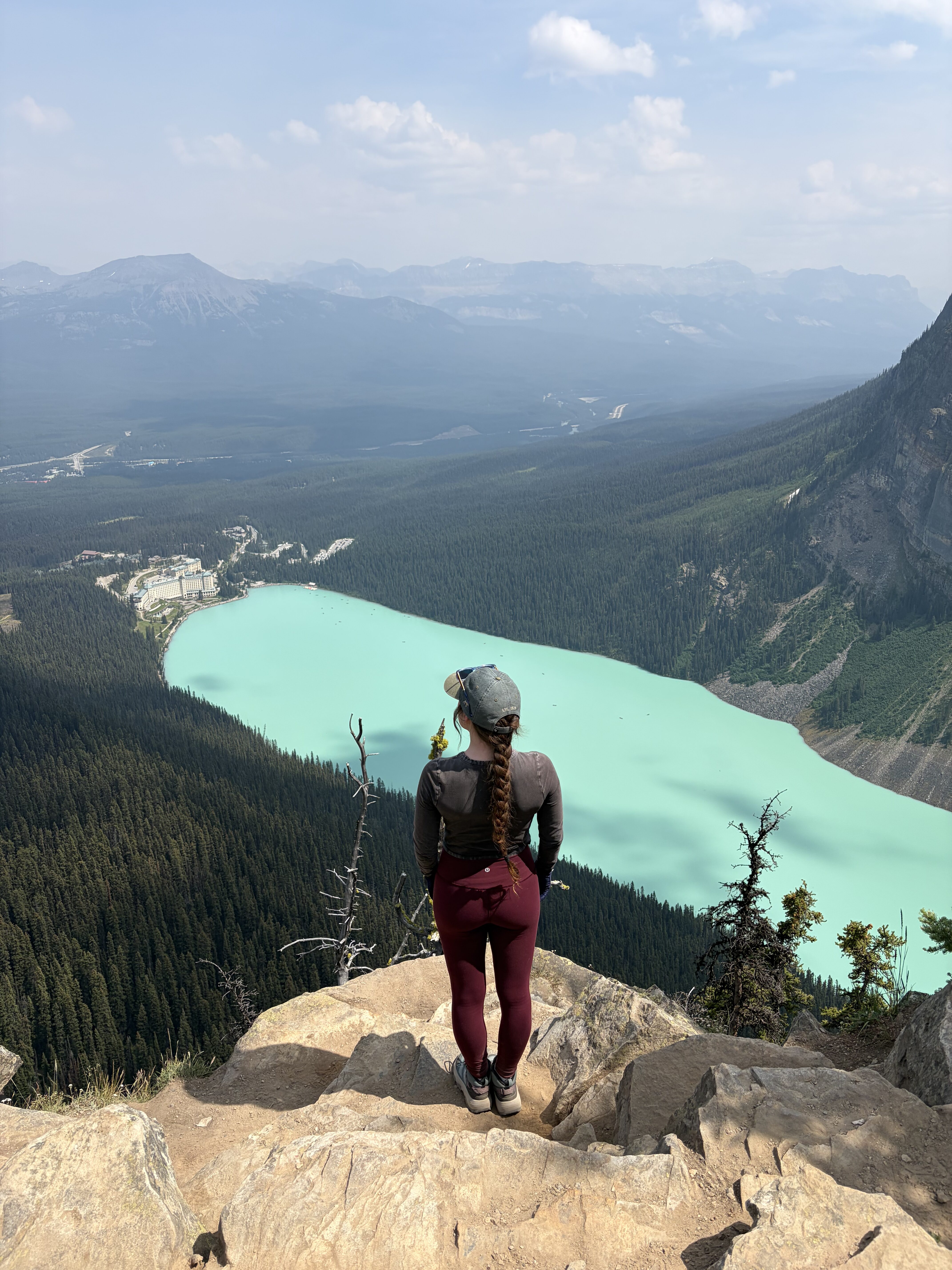 A woman standing on a rock at Big Beehive gazing out upon the aquamarine Lake Louise.