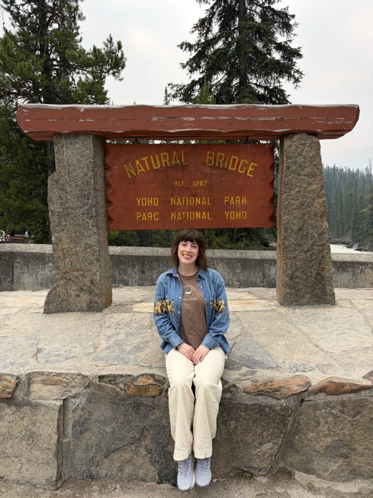 Bella sitting in front of the weathered sign, Yoho National Park, Natural Bridge. 